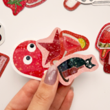 Kırmızı temalı, yıldız desenli hologram sticker paketinin farklı açılardan çekilmiş fotoğrafı