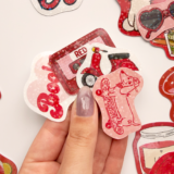 Kırmızı temalı, yıldız desenli hologram sticker paketinin farklı açılardan çekilmiş fotoğrafı