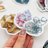 Mineral ve kristal temalı 34 adet suya dayanıklı vinil sticker setinin pürüzsüz bir yüzeydeki görünümü.